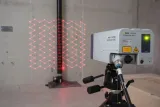 Appareil laser à tête de balayage Polytec PSV-500 sur trépied avec lignes laser rouges sur un mur.