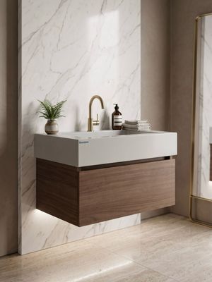 Meuble de salle de bain en bois brun avec mur en marbre blanc, robinetterie dorée et lavabo en pierre bleue.
