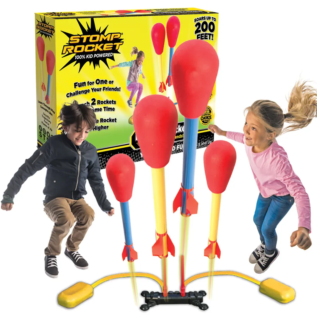 A child jumps while playing with a Stomp Rocket toy set, featuring colorful rockets on a launch pad, with a vibrant, engaging box in the background.