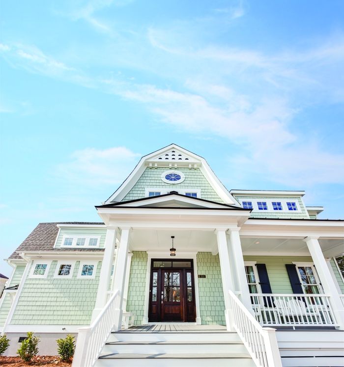 Exterior rendering of a coastal-inspired home plan with shingle siding, decorative gable detailing, and a raised front porch.