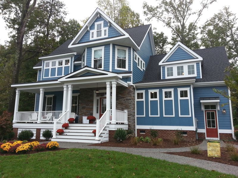 Exterior rendering of a coastal-style home plan with a prominent front porch, mixed siding materials, and stone accents.