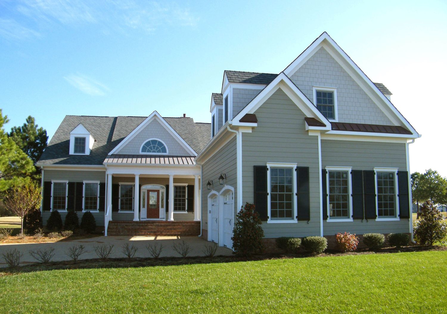 Exterior rendering of a traditional neighborhood home plan with symmetrical façade, black shutters, covered front porch.