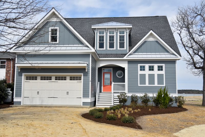 Exterior rendering of a coastal-style residential home plan with gray siding, metal roof details, and a covered front entry.