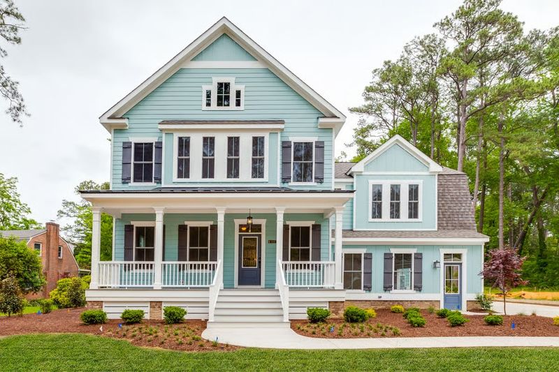 Exterior rendering of a coastal-inspired two-story home plan with light blue siding, white trim, a wide covered front porch.