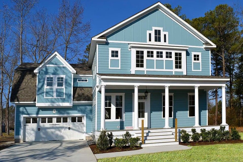 Front exterior view of a two-story blue house with white trim, a covered porch, attached garage, and balcony.