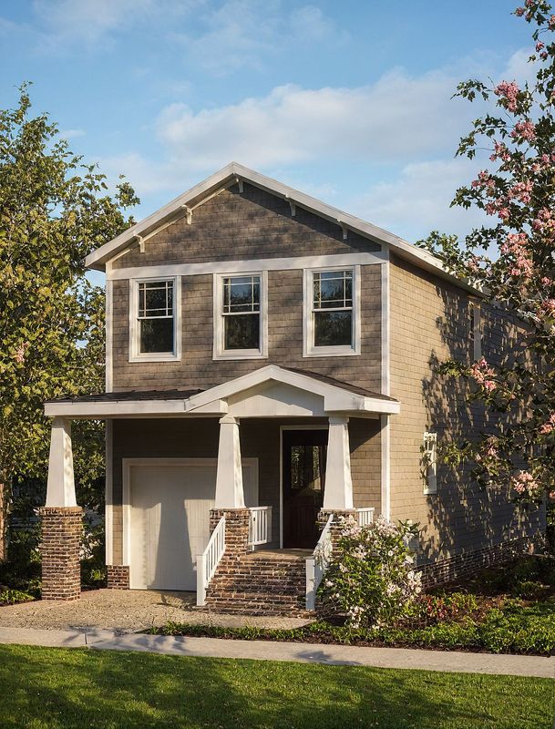 Exterior rendering of a narrow coastal-style home plan with tan siding, white trim, stone accents, and elevated front porch.