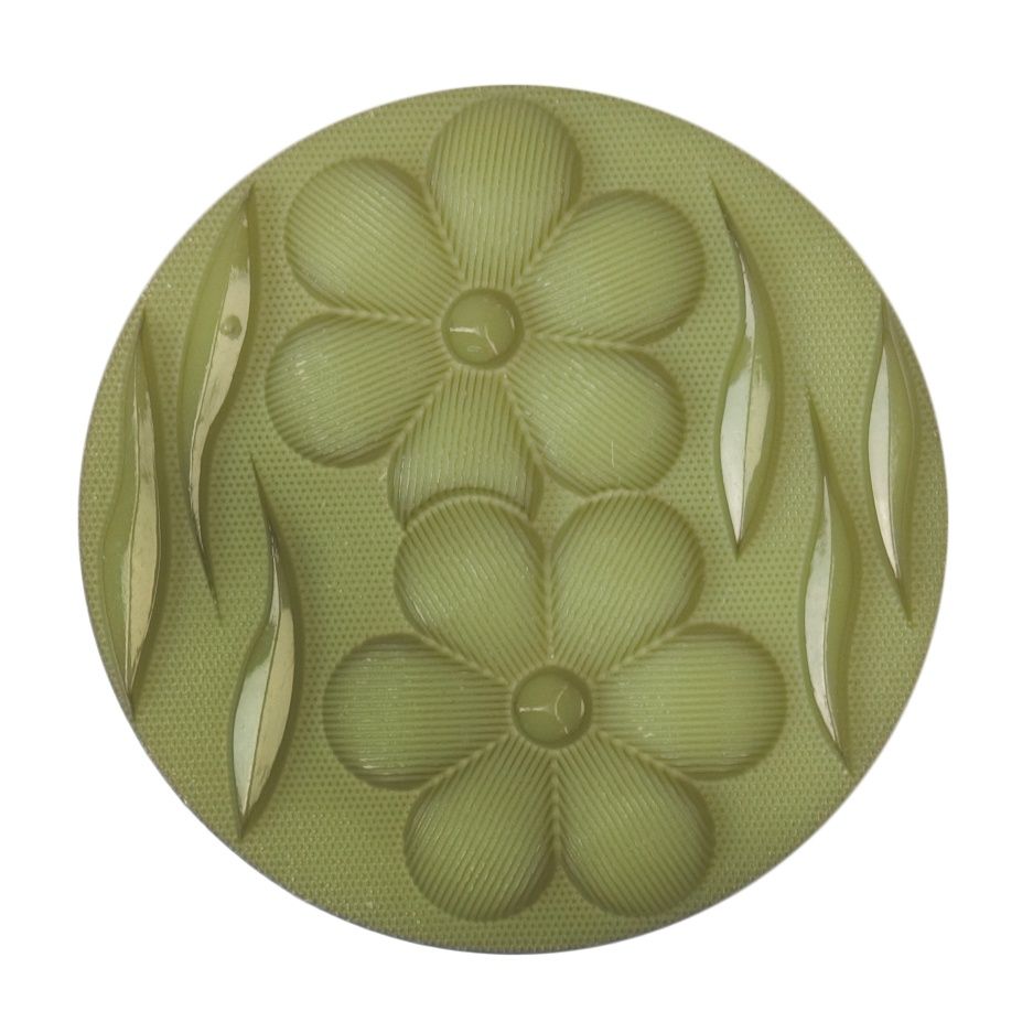 A round green button with a raised flower and leaf design.