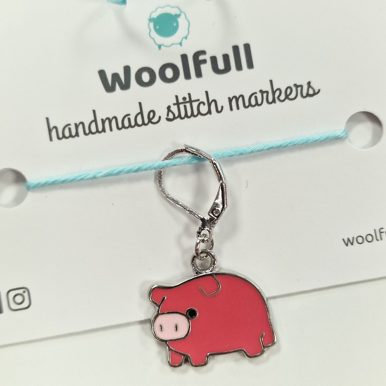 A pink enamel pig shaped stitch marker.