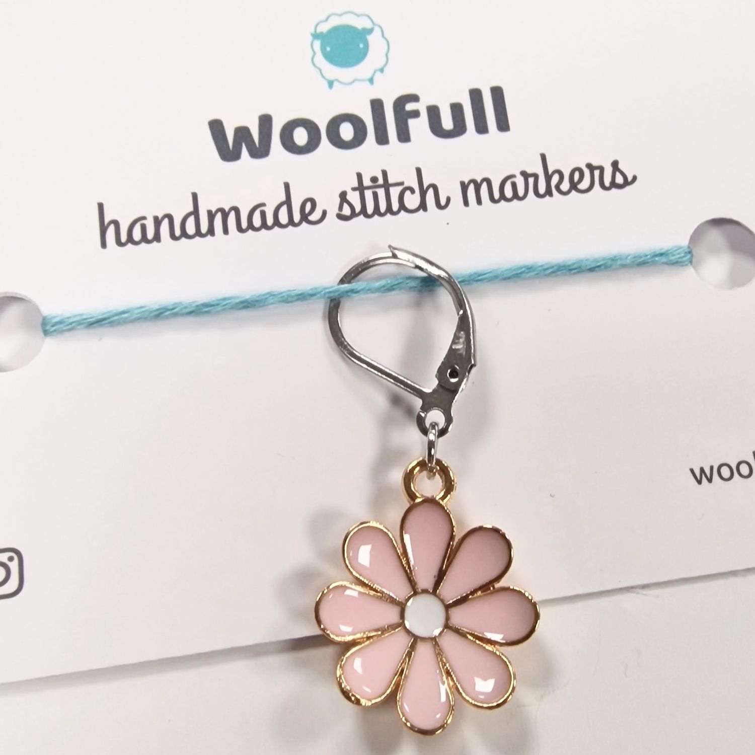 A pink flower shaped stitch marker.