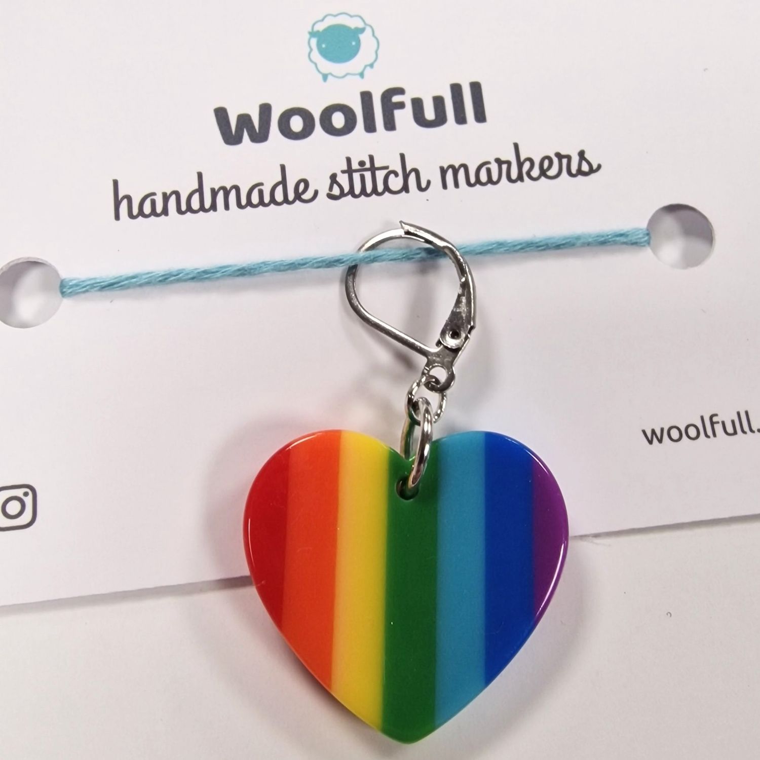 A plastic rainbow heart shaped stitch marker.