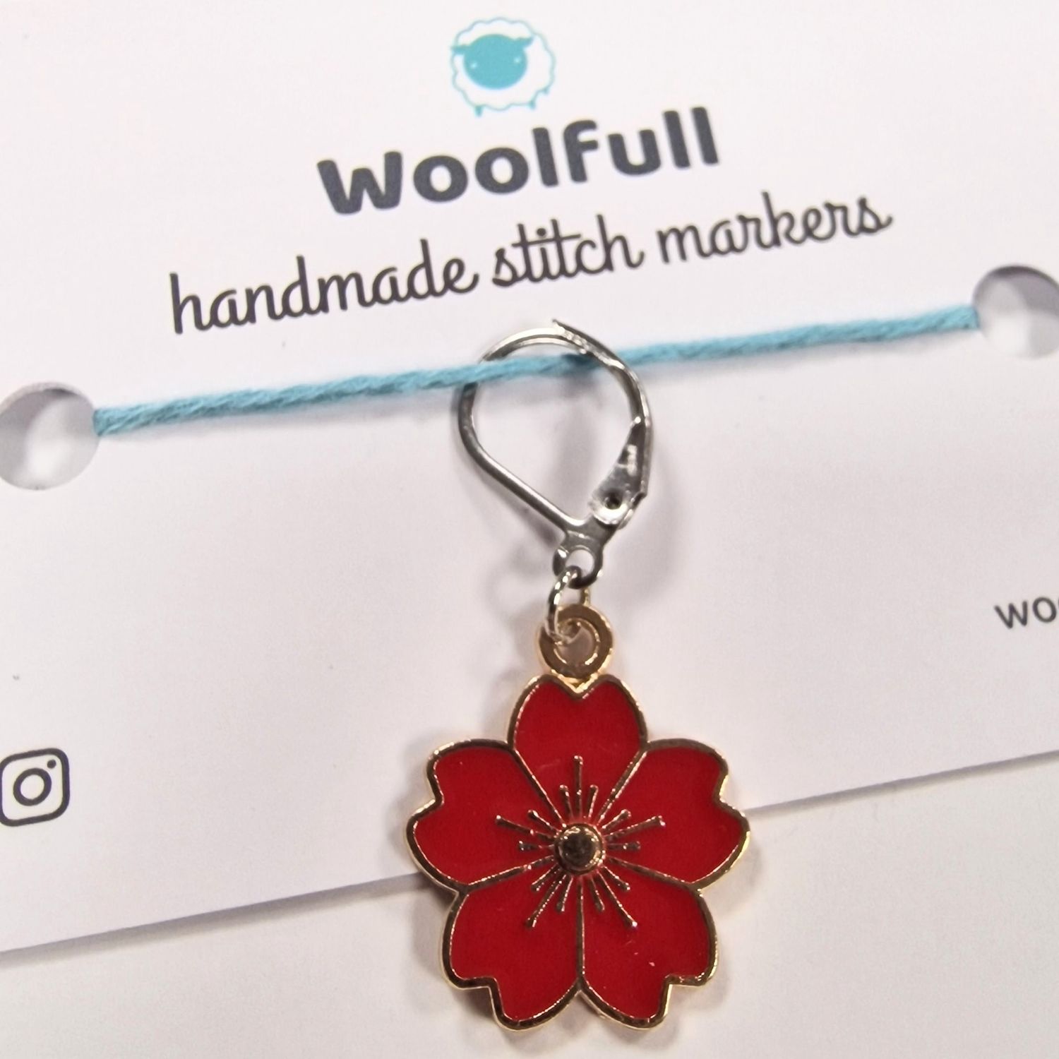 A red flower shaped stitch marker.