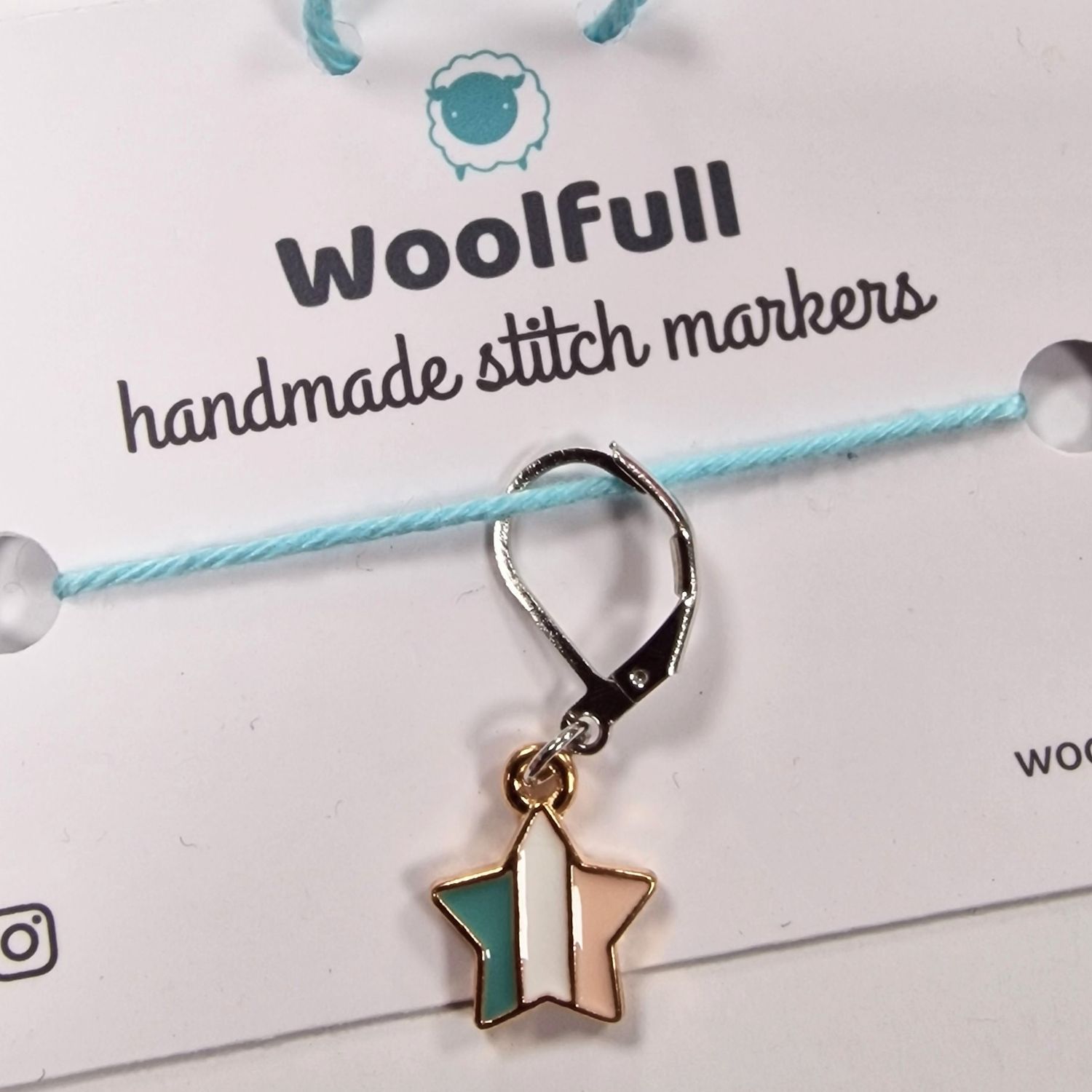 A blue, white and light pink striped star shaped stitch marker.