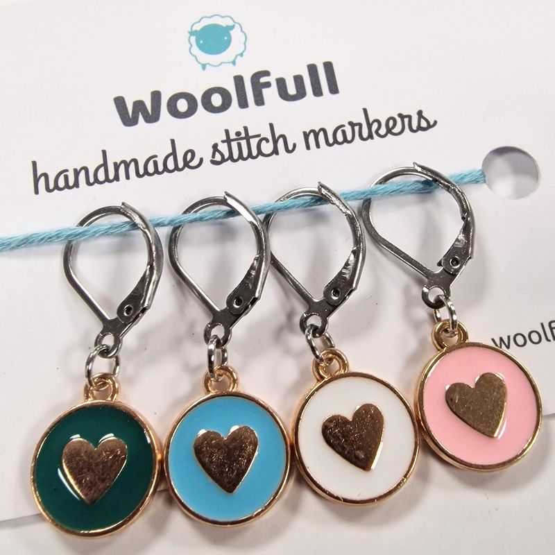 4 coloured circular stitch markers with hearts on them.