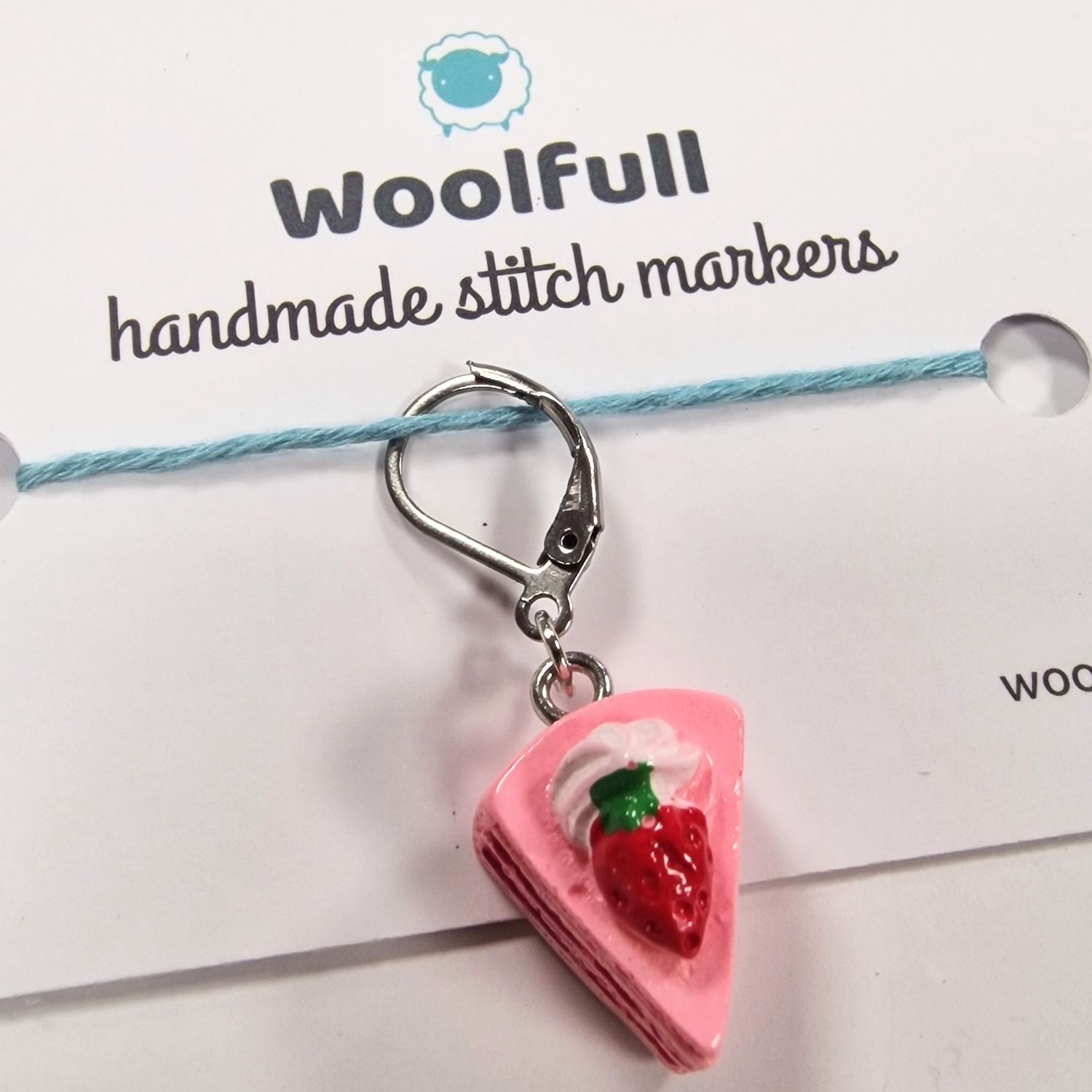 A pink slice of cake shaped stitch marker.