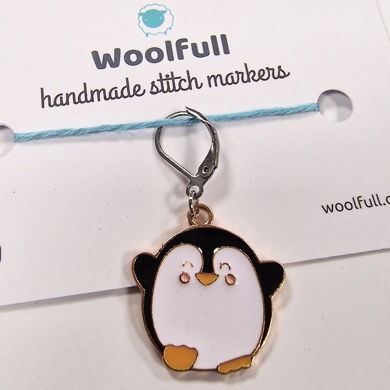 A metal penguin shaped stitch marker.