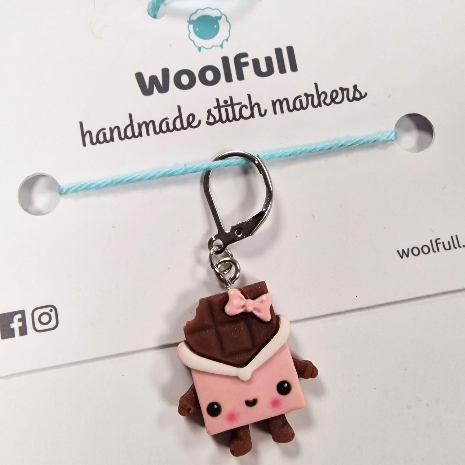 A chocolate shaped stitch marker with a smiley face and a bow.