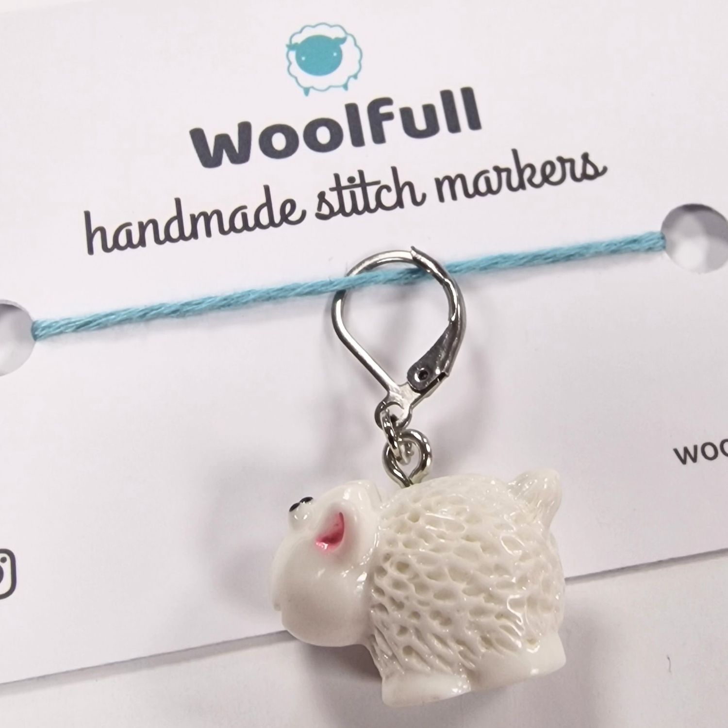 A white plastic sheep shaped stitch marker.