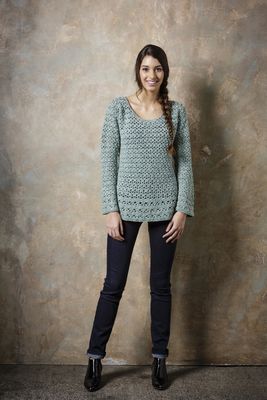 A woman is wearing an dusky blue crocheted tunic.