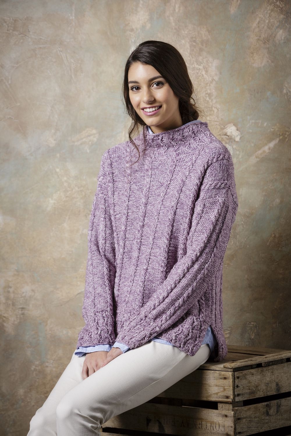 A woman is wearing a light purple knitted sweater.