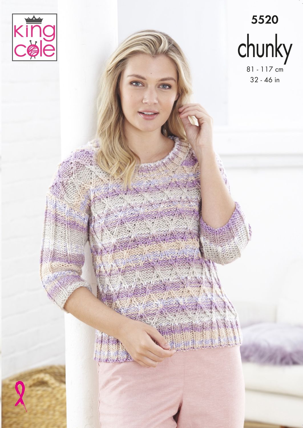 A woman is wearing a cable knit sweater in a variegated pink, cream and grey yarn.