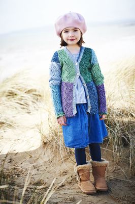 A girl is wearing a knitted cardigan in a variegated blue, purple and green yarn.