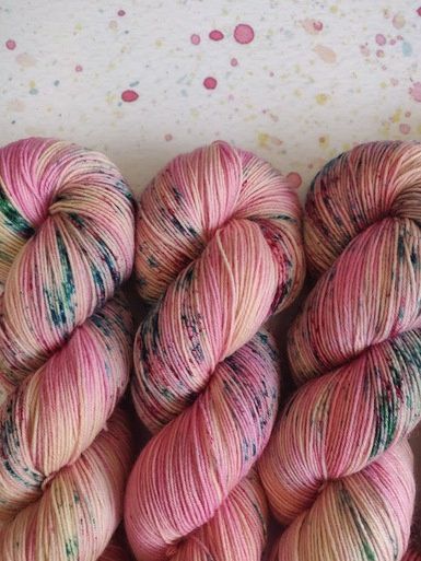 A close up of the skeins, in pale pink with blue speckles.