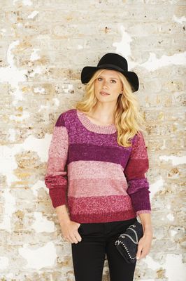 A woman is wearing a knitted sweater in a variegated pink yarn.