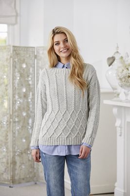 A woman is wearing a pale grey cable knit sweater.