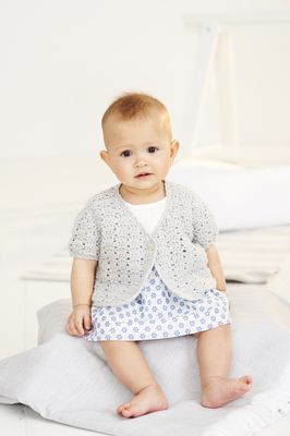 A baby is wearing a pale grey crocheted cardigan.