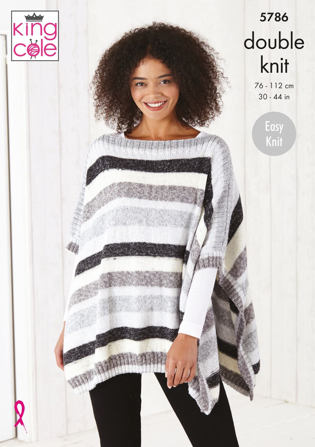 A woman is wearing a knitted poncho in black, white and grey stripes.