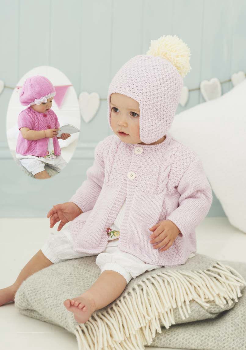A baby is wearing a pale pink knitted cardigan and matching hat.