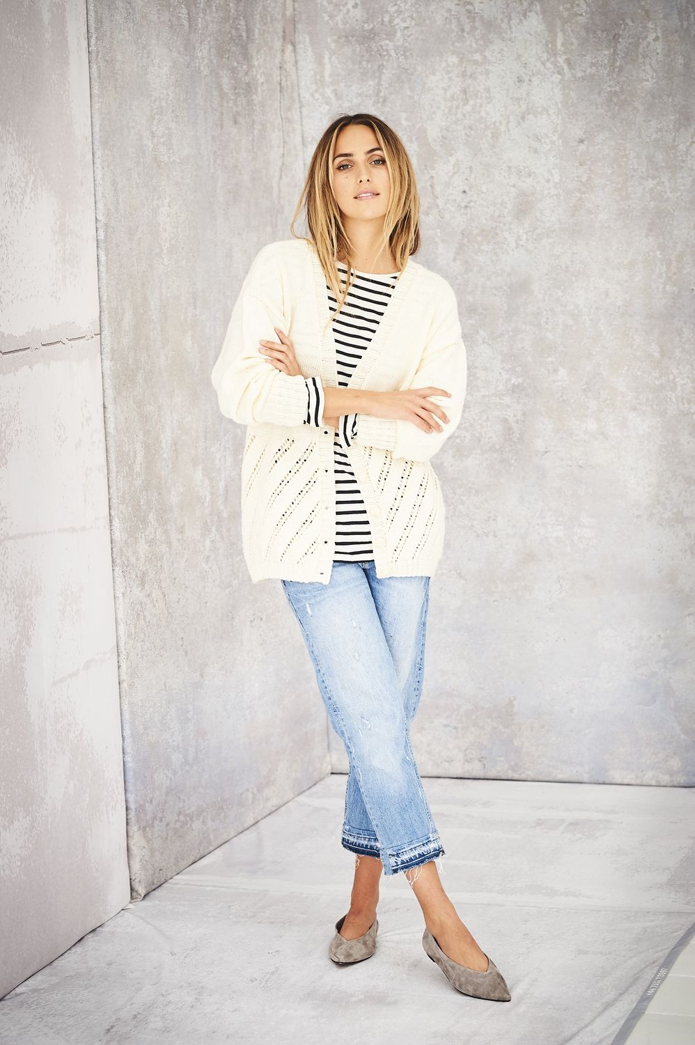 A woman is wearing a cream knitted cardigan.