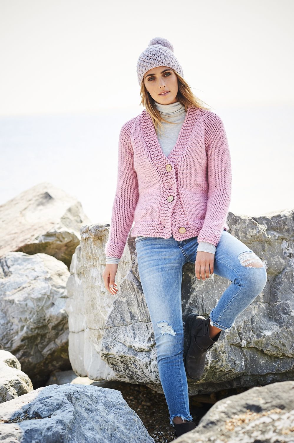 A woman is wearing a light blue knitted cardigan.