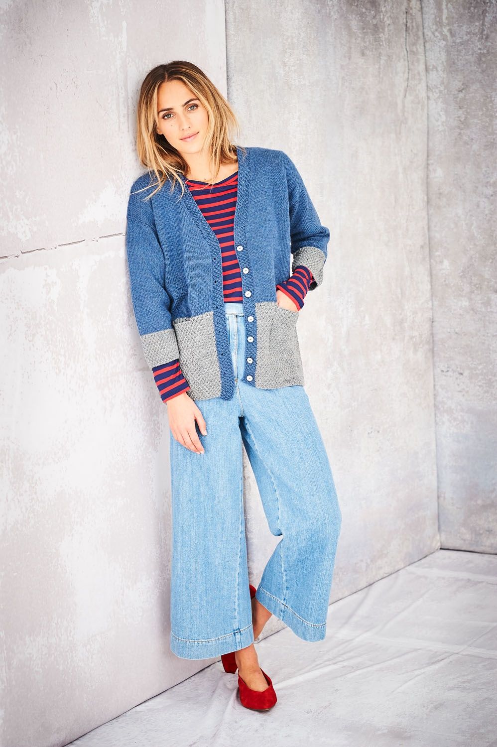A woman is wearing a blue and grey knitted cardigan.