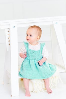 The front view of a baby wearing a blue knitted dress.