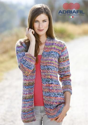A woman is wearing a knitted cardigan in a variegated blue, red and green yarn.