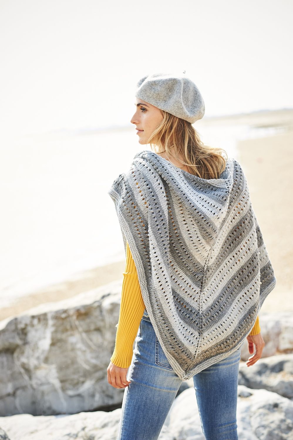 A woman is wearing a grey knitted shawl.