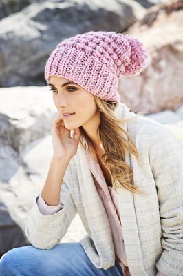 A woman is wearing a pink knitted hat with a pink pompom.