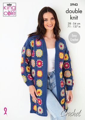 A woman is wearing a long crocheted cardigan, made of multicoloured granny squares that are all bordered and joined in dark blue.