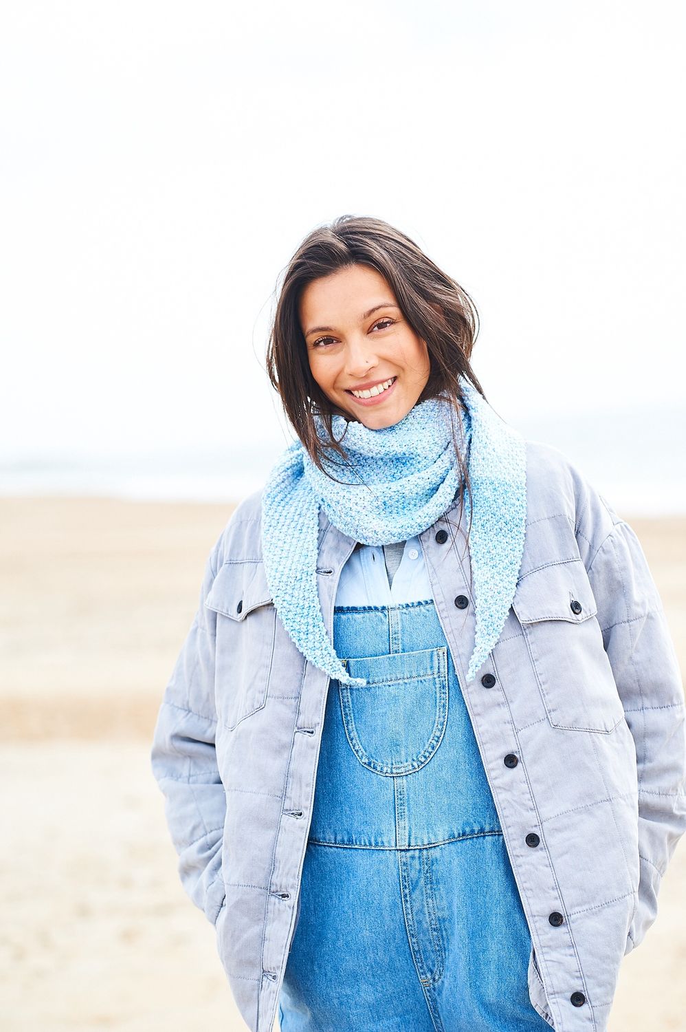 A woman is wearing a knitted shawl in shades of blue.
