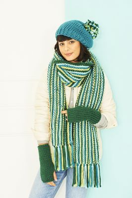 A woman is wearing a green and blue stripy knitted scarf and a blue knitted hat with a blue and green pompom.