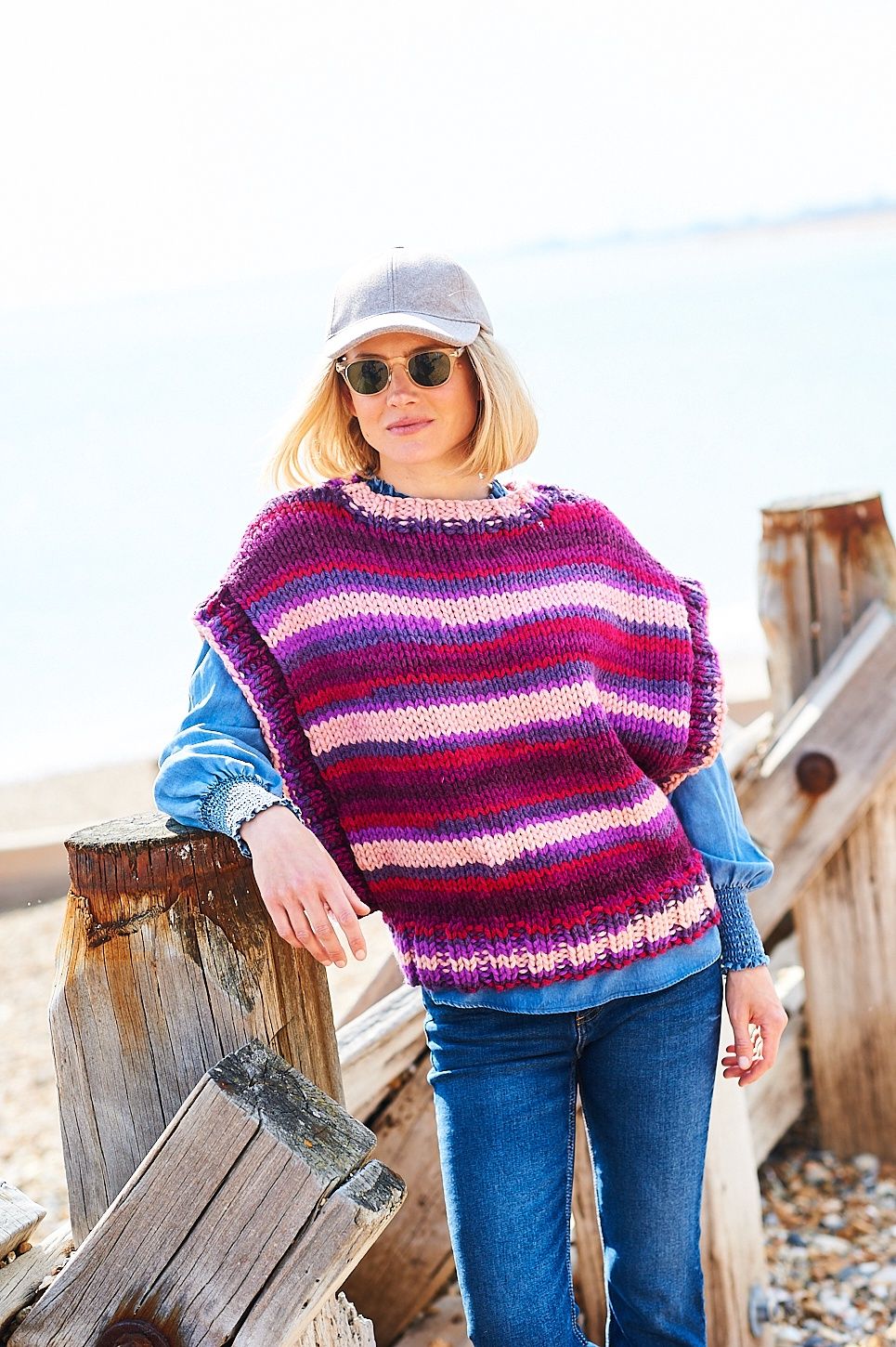 A woman is wearing a variegated knitted tank top in shades of blue, pink, purple and red.