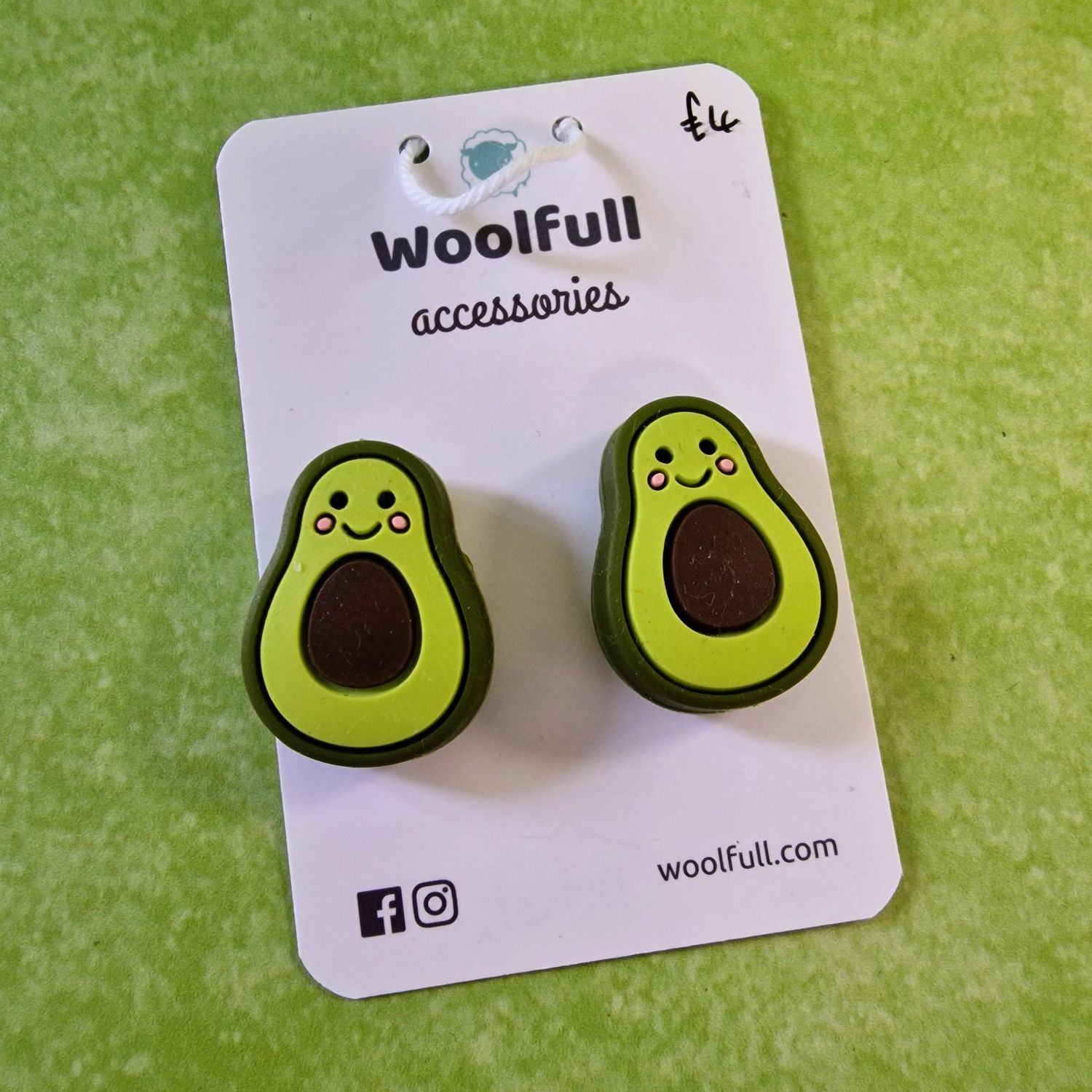 A green background with a pair of avocado shaped point protectors mounted on a white card.