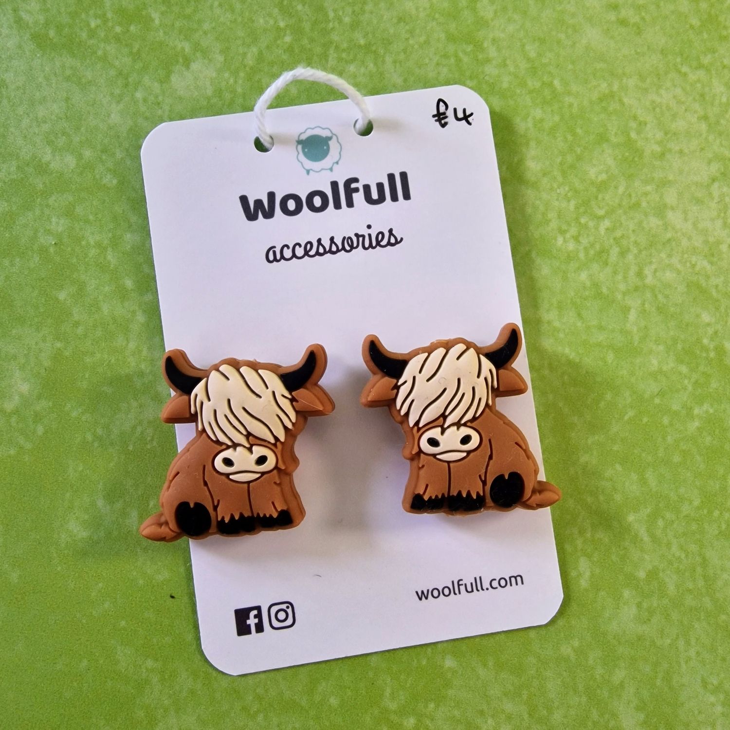 A green background with a pair of highland cow shaped point protectors mounted on a white card.