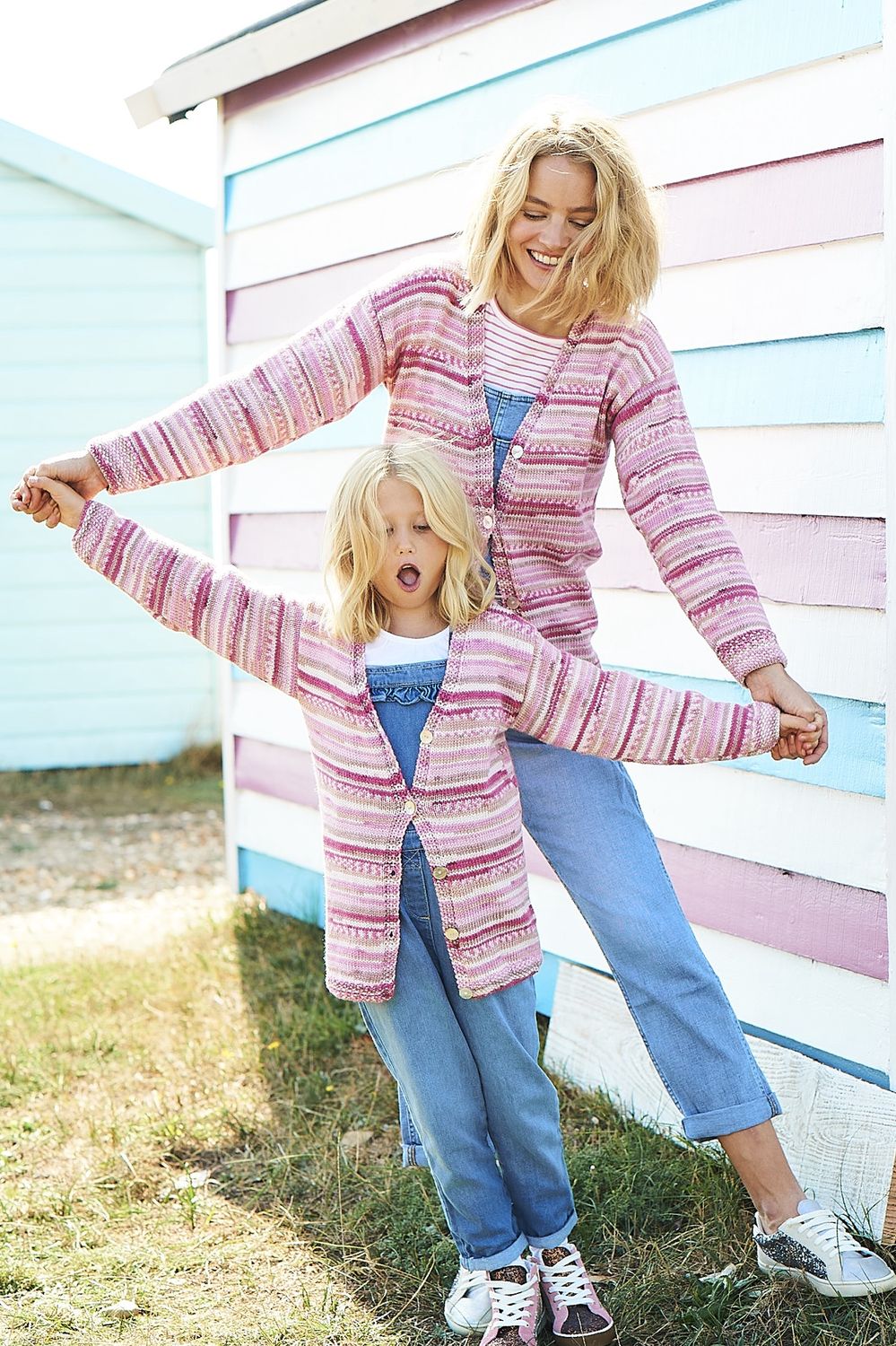 A woman and a girl are wearing matching knitted cardigans in a variegated pink yarn.