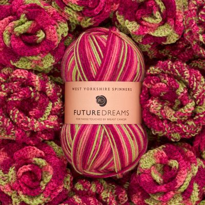 A ball of variegated pink and green yarn, on a background of knitted and crocheted flowers from the same yarn.