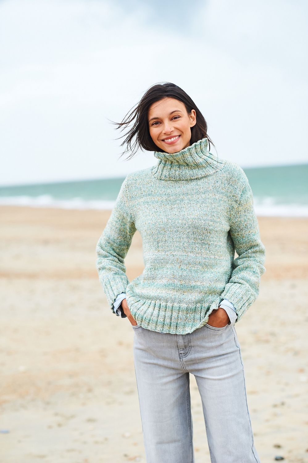 A woman is wearing a knitted sweater in shades of green.