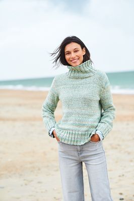 A woman is wearing a knitted sweater in shades of green.
