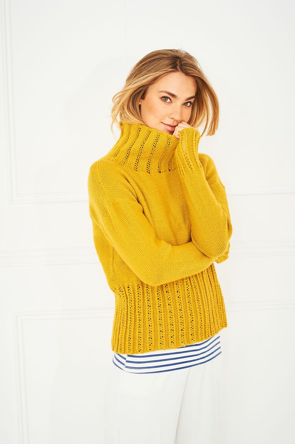 A woman is wearing a mustard yellow knitted sweater.