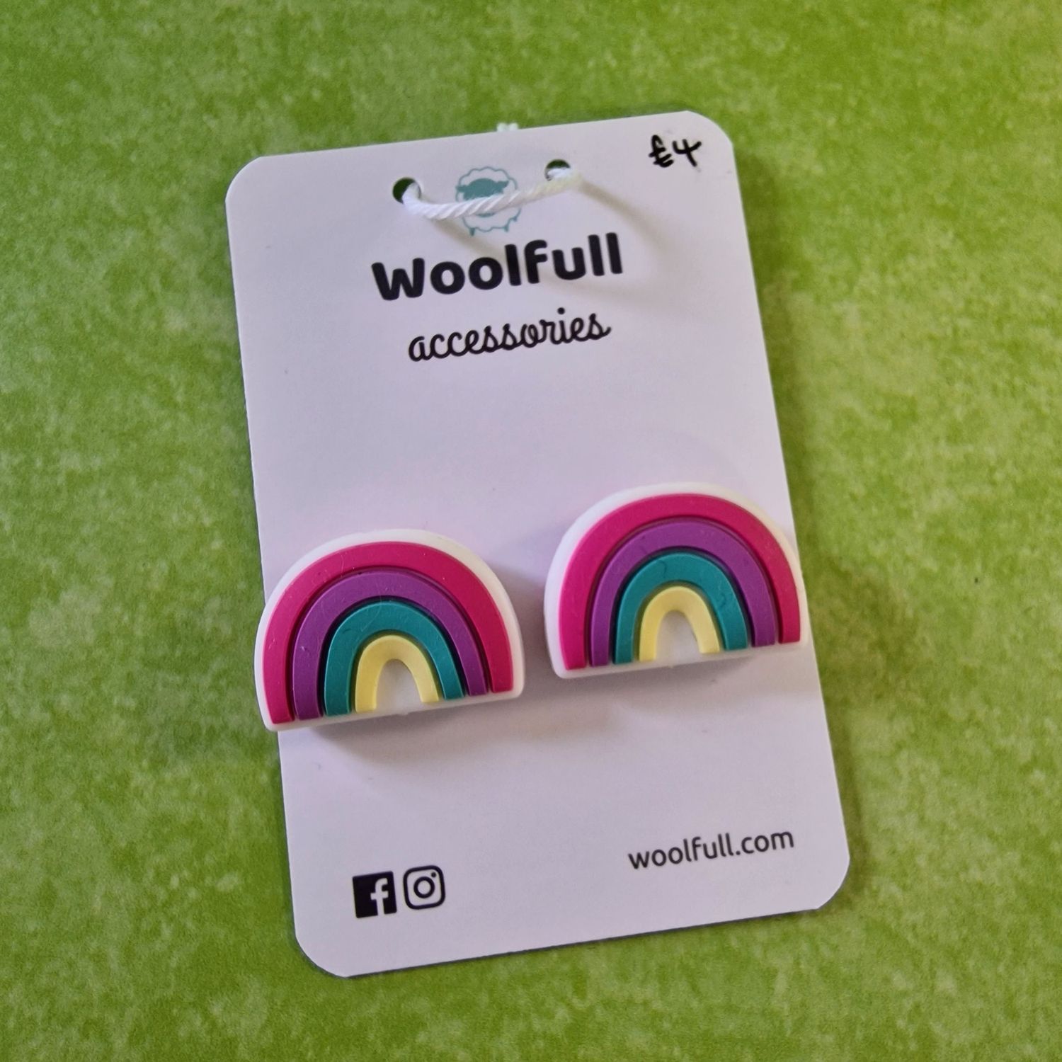 A green background with a pair of rainbow shaped point protectors mounted on a white card.